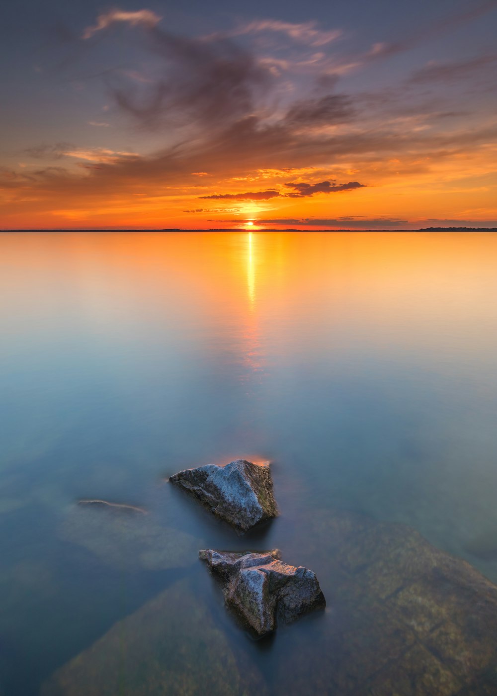 gray rocks on body of water during sunset