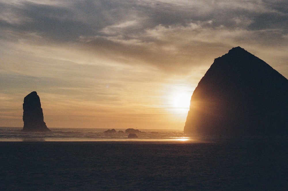 Silhouette d’une formation rocheuse près d’un plan d’eau au coucher du soleil