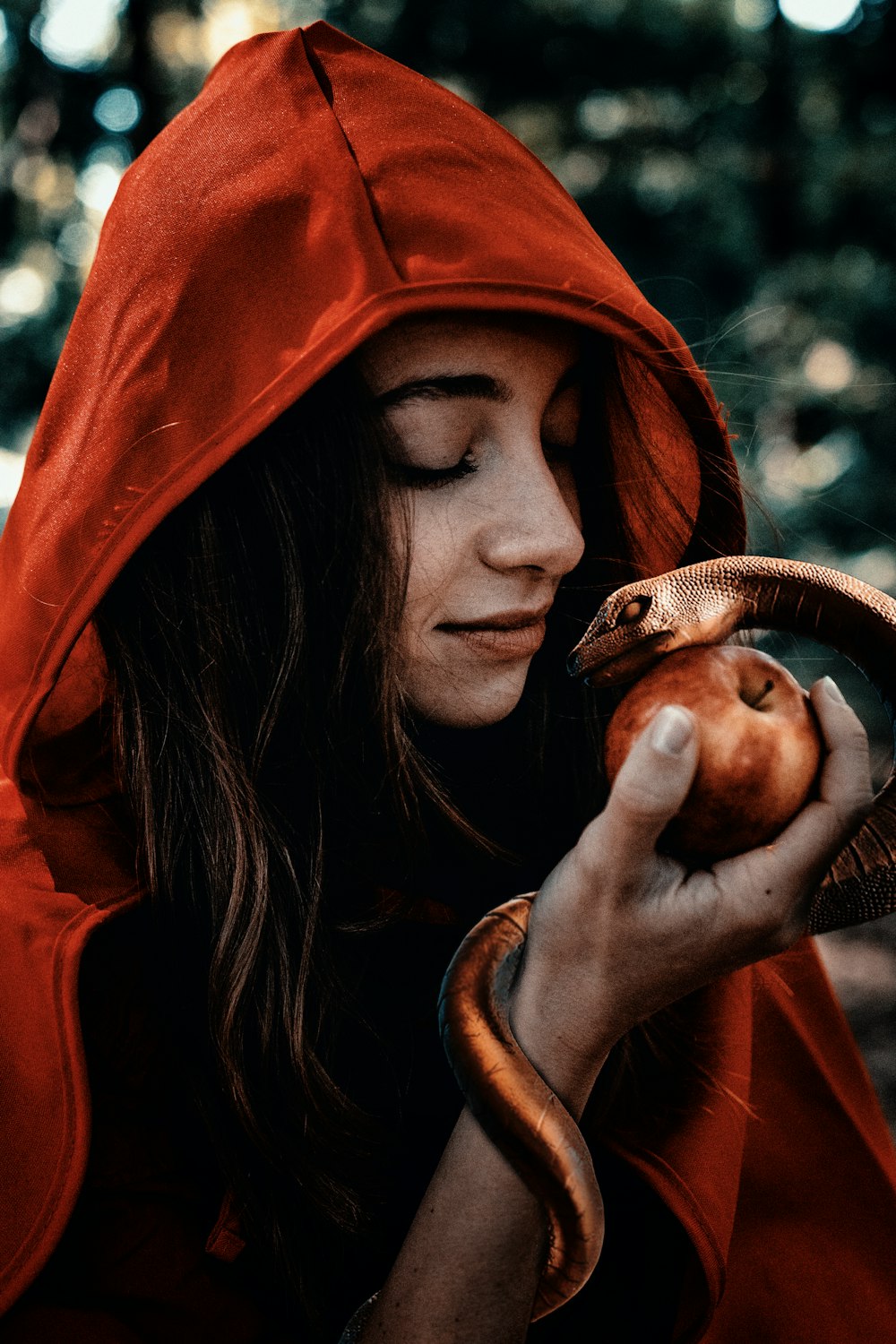 woman in orange hoodie holding brown snake