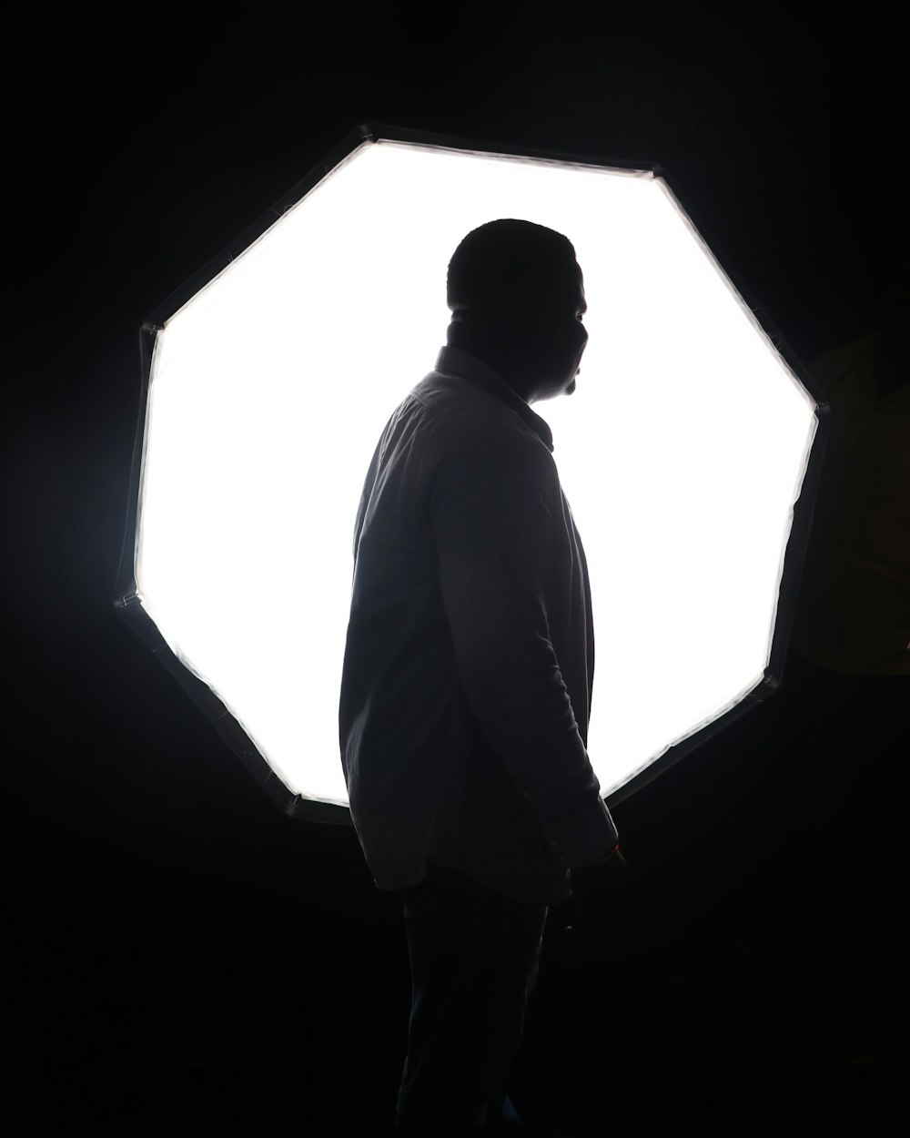 man in white dress shirt standing in front of white wall