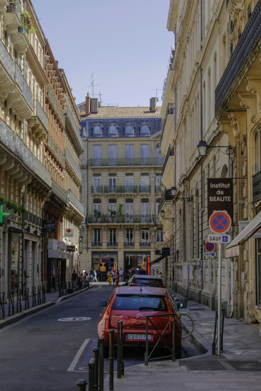 red car on road in between buildings during daytime