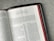An open Bible lies on a gray fabric surface, displaying the pages from 'The Letter of Paul to the Galatians'. The text is in a double-column format with chapter headings and verses clearly visible. The edges of the pages are a reddish color, and the book has a black cover with golden detailing along the edge.