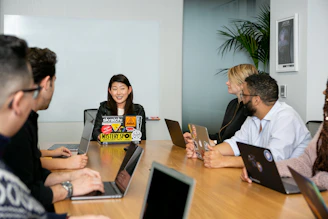 A team meeting around a table reviewing cloud architecture plans on a laptop.