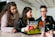 three people around a laptop with stickers on it