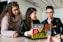 three people around a laptop with stickers on it