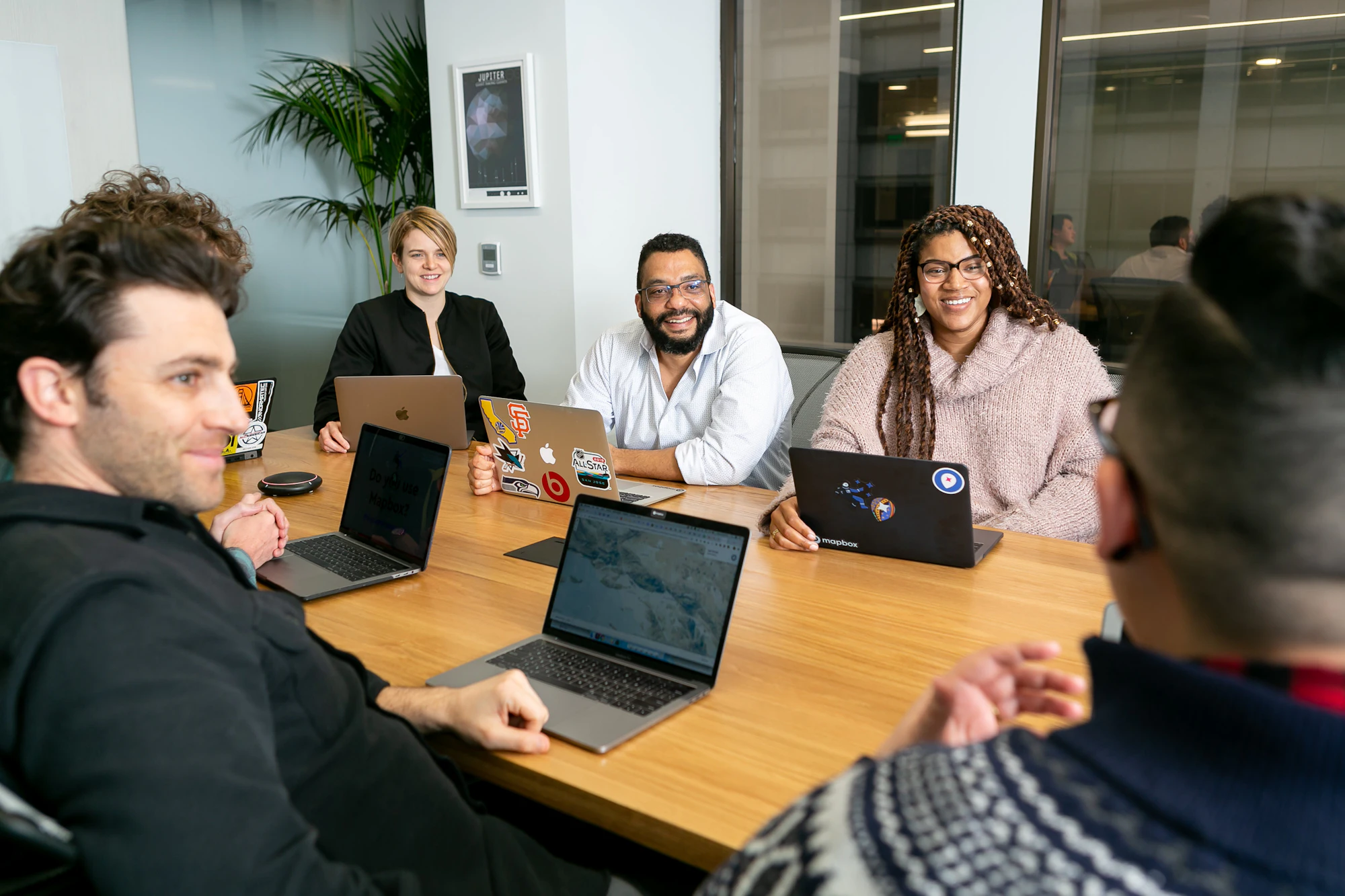 A diverse advisory team in a board meeting, working on laptops around a conference table