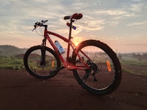 red and black full suspension mountain bike on brown sand during daytime