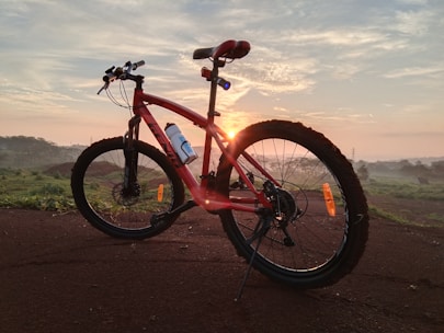 red and black full suspension mountain bike on brown sand during daytime