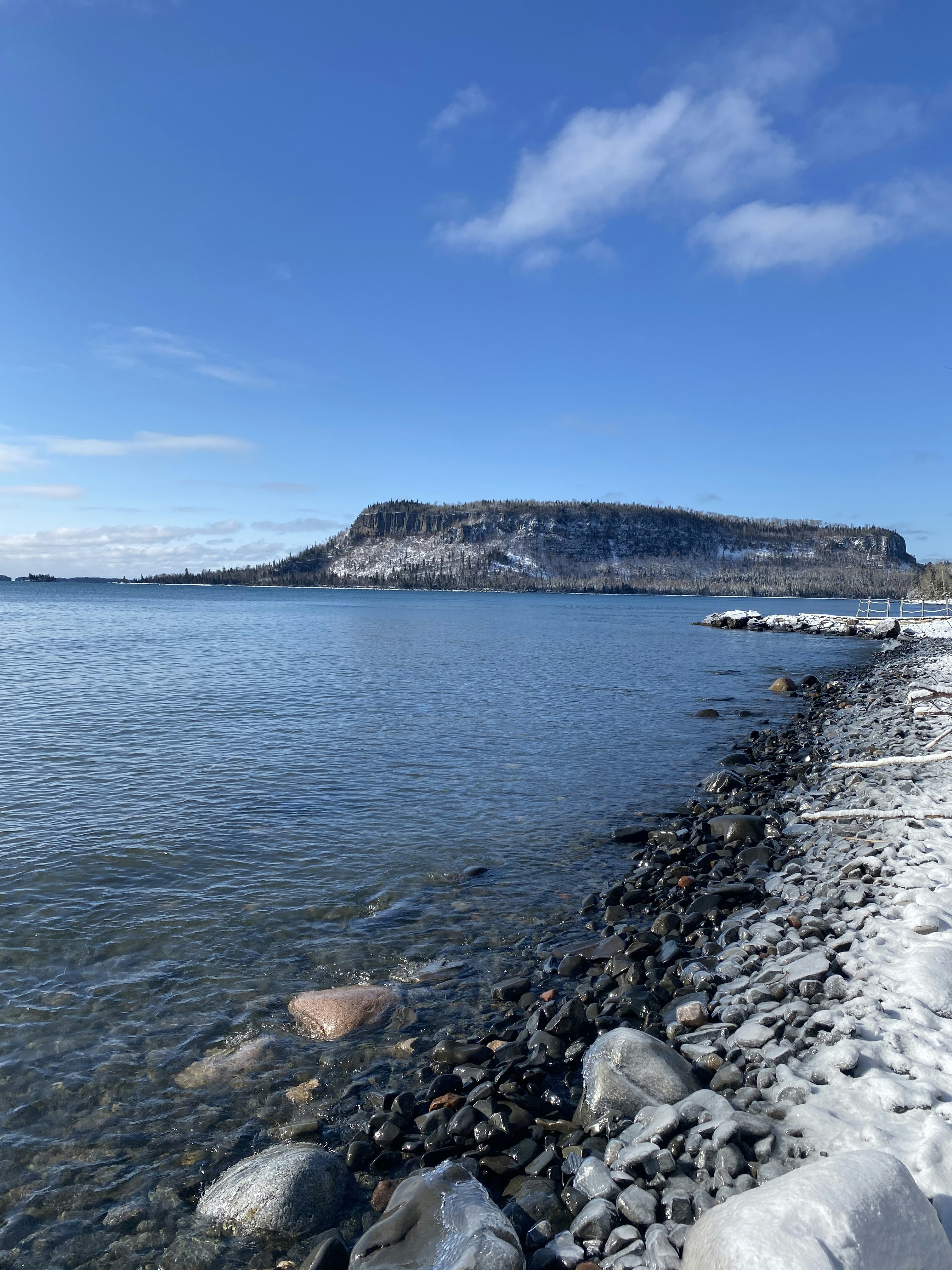 body of water near mountain under blue sky during daytime