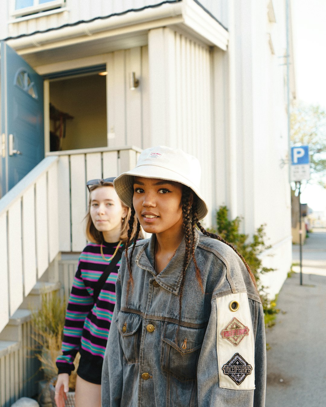 woman in white hat and blue and white striped shirt standing near white building during daytime