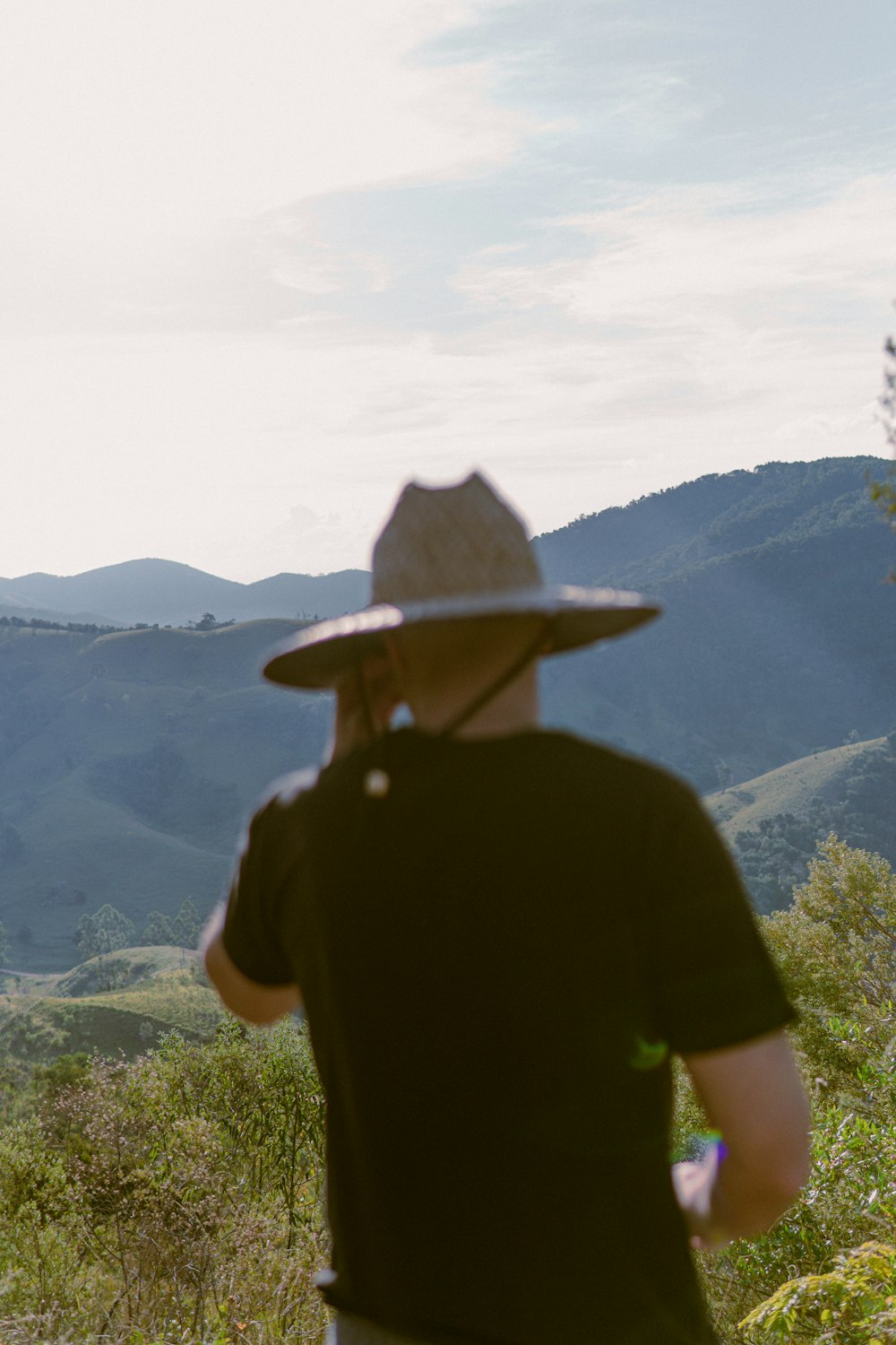 man in black shirt wearing white hat standing on top of mountain during daytime