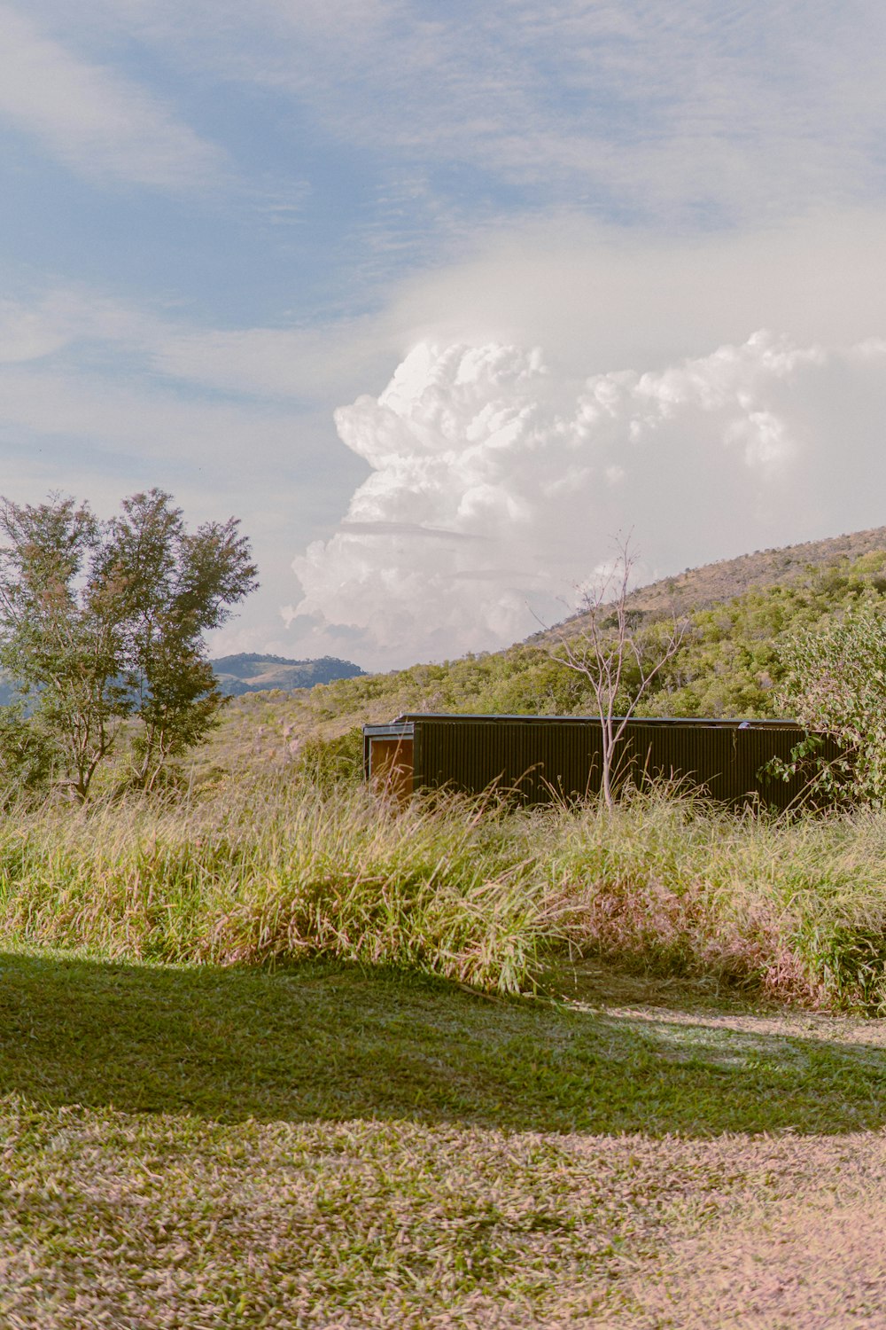 brown wooden house on green grass field under white clouds during daytime