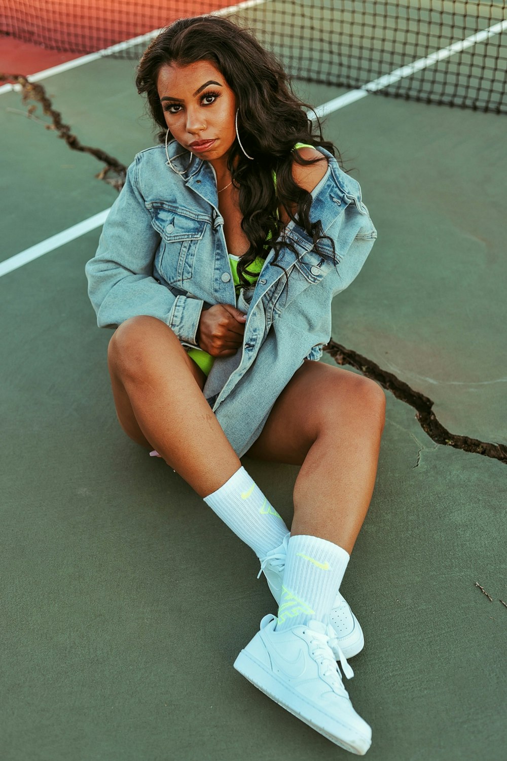 woman in blue denim jacket and white socks sitting on gray concrete floor