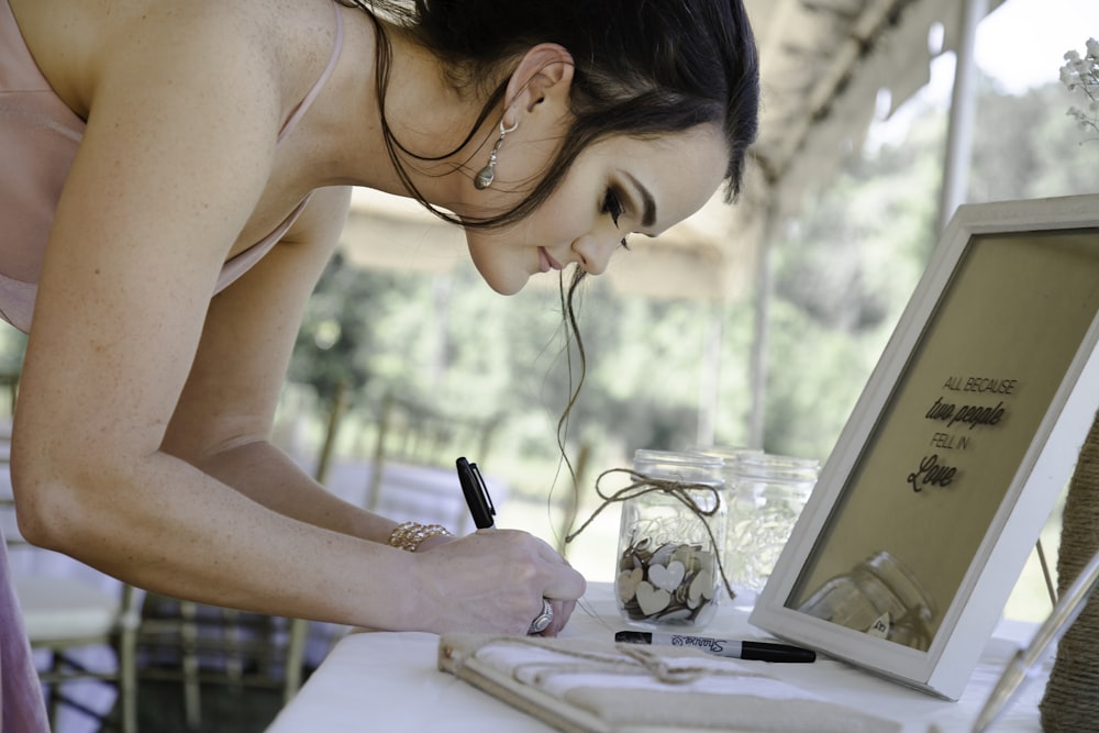 woman in white tank top writing on white paper