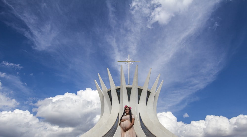 woman in black tank top standing on white round structure under blue and white sunny cloudy