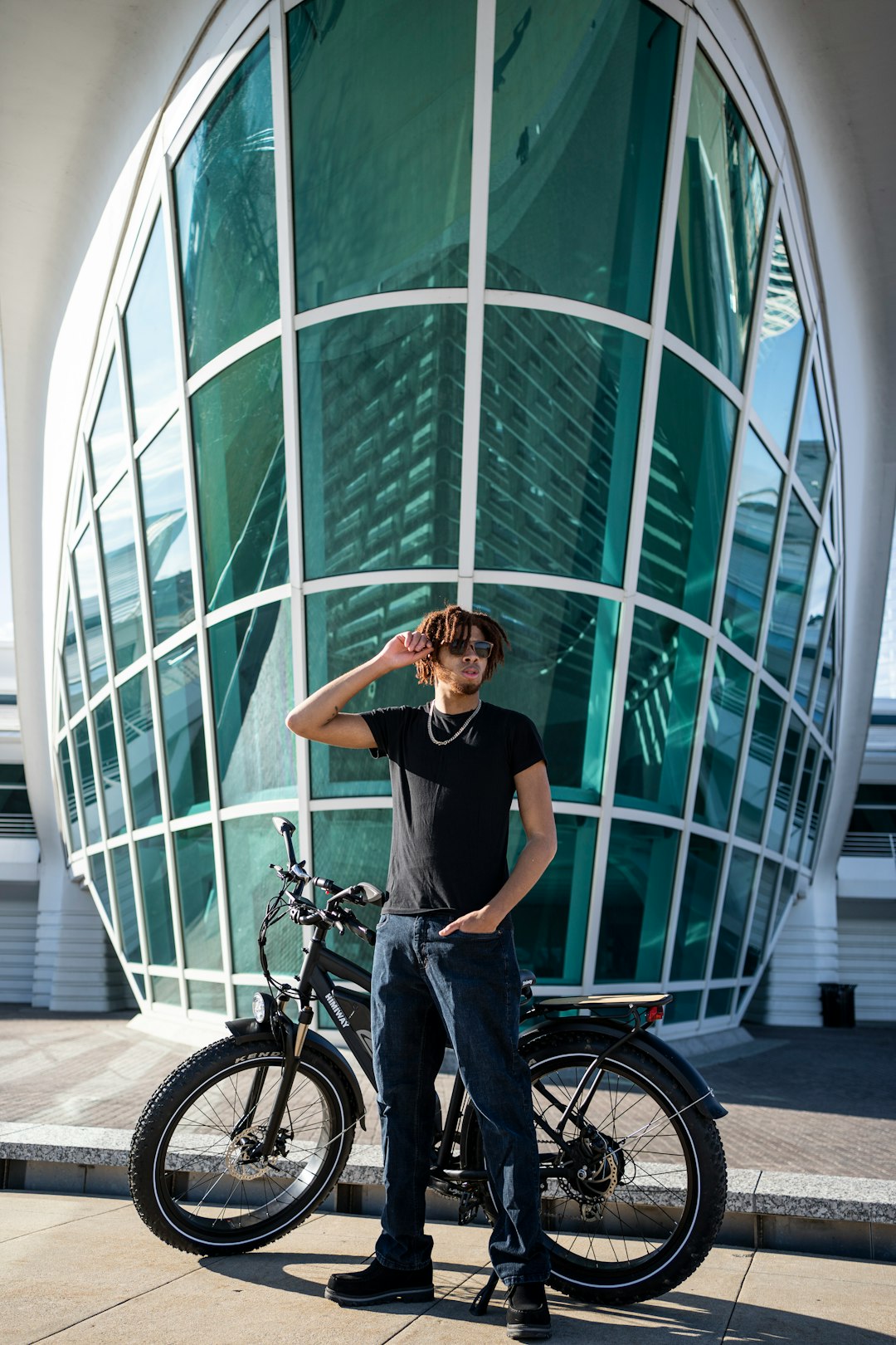 woman in black t-shirt and blue denim jeans riding on bicycle