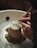 Hands are shaping a clay pot on a spinning pottery wheel, with delicate tools carving intricate patterns into the base. The setting is rustic and focused on a detailed view of the craftsmanship involved in pottery making.