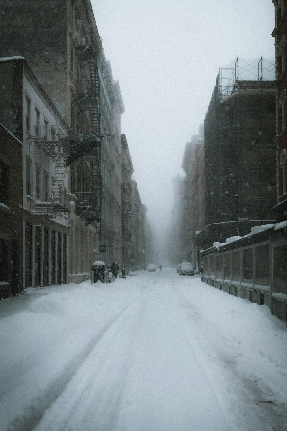 Carretera cubierta de nieve entre edificios de hormigón marrón durante el día