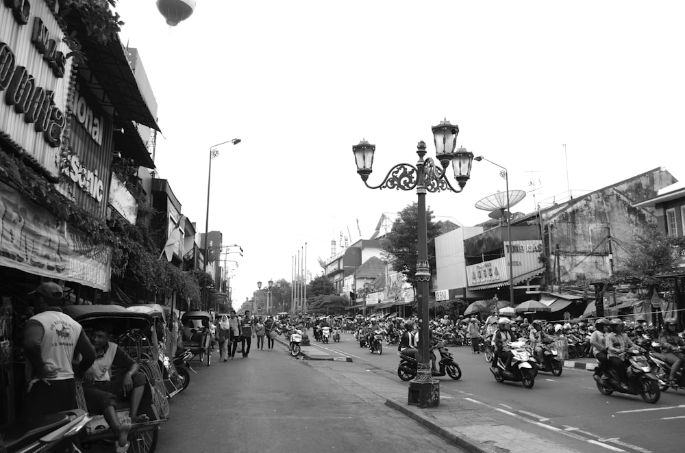 Foto in scala di grigi di persone in sella a una motocicletta su strada