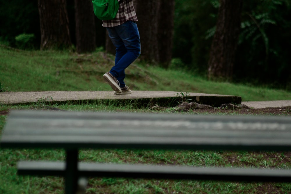 person in blue denim jeans standing on brown wooden bench