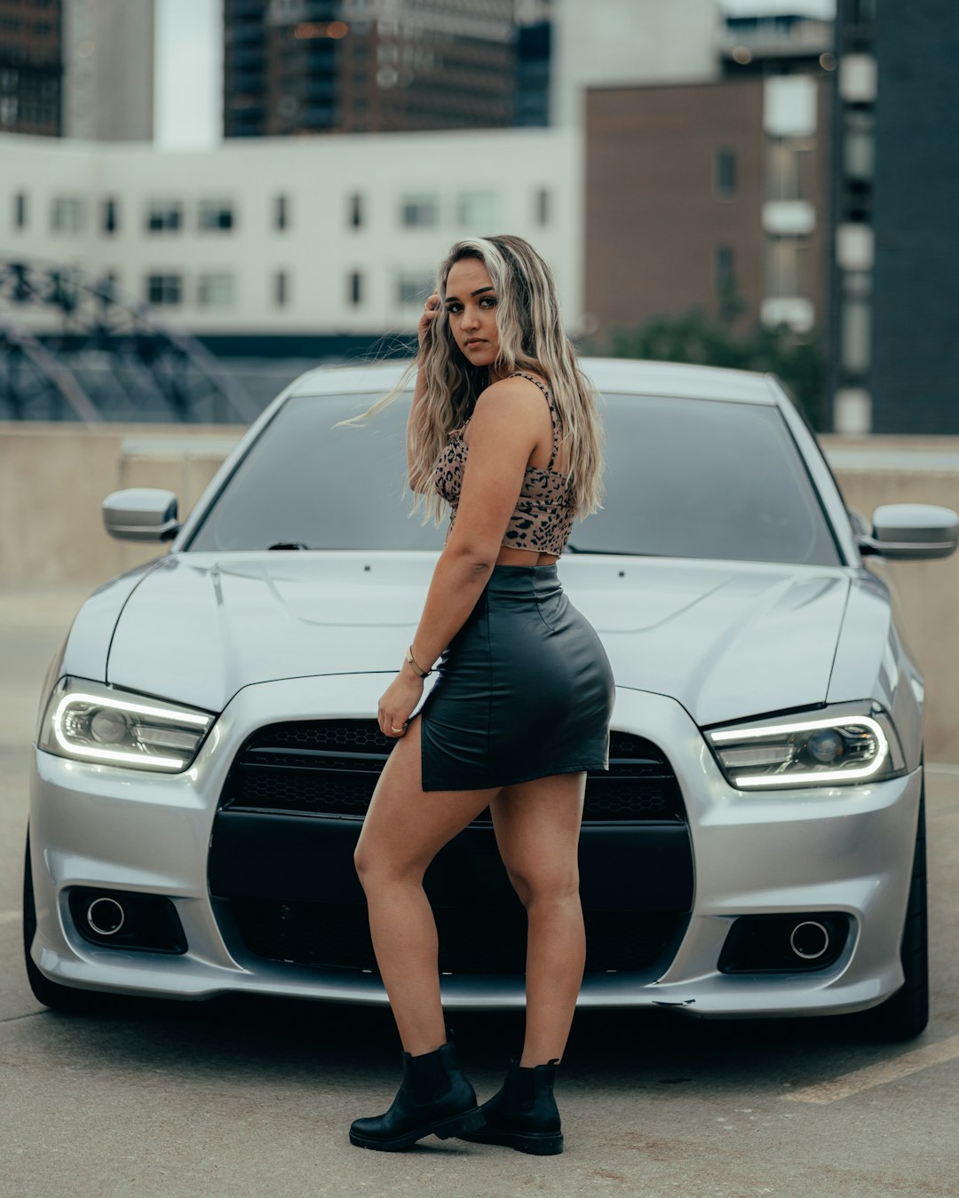 woman in black mini dress standing beside white car during daytime