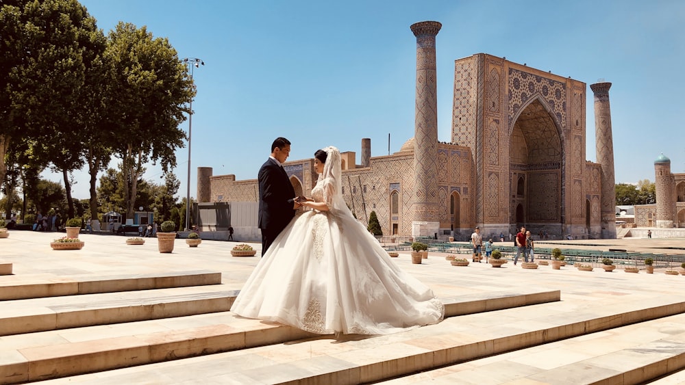 man and woman in wedding dress walking on the street during daytime