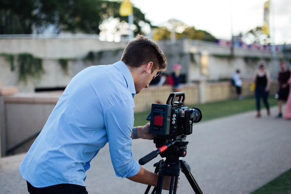 man in blue dress shirt holding black dslr camera