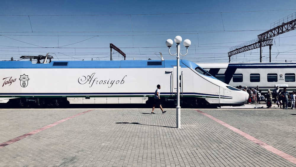 a blue and white train parked next to a train station