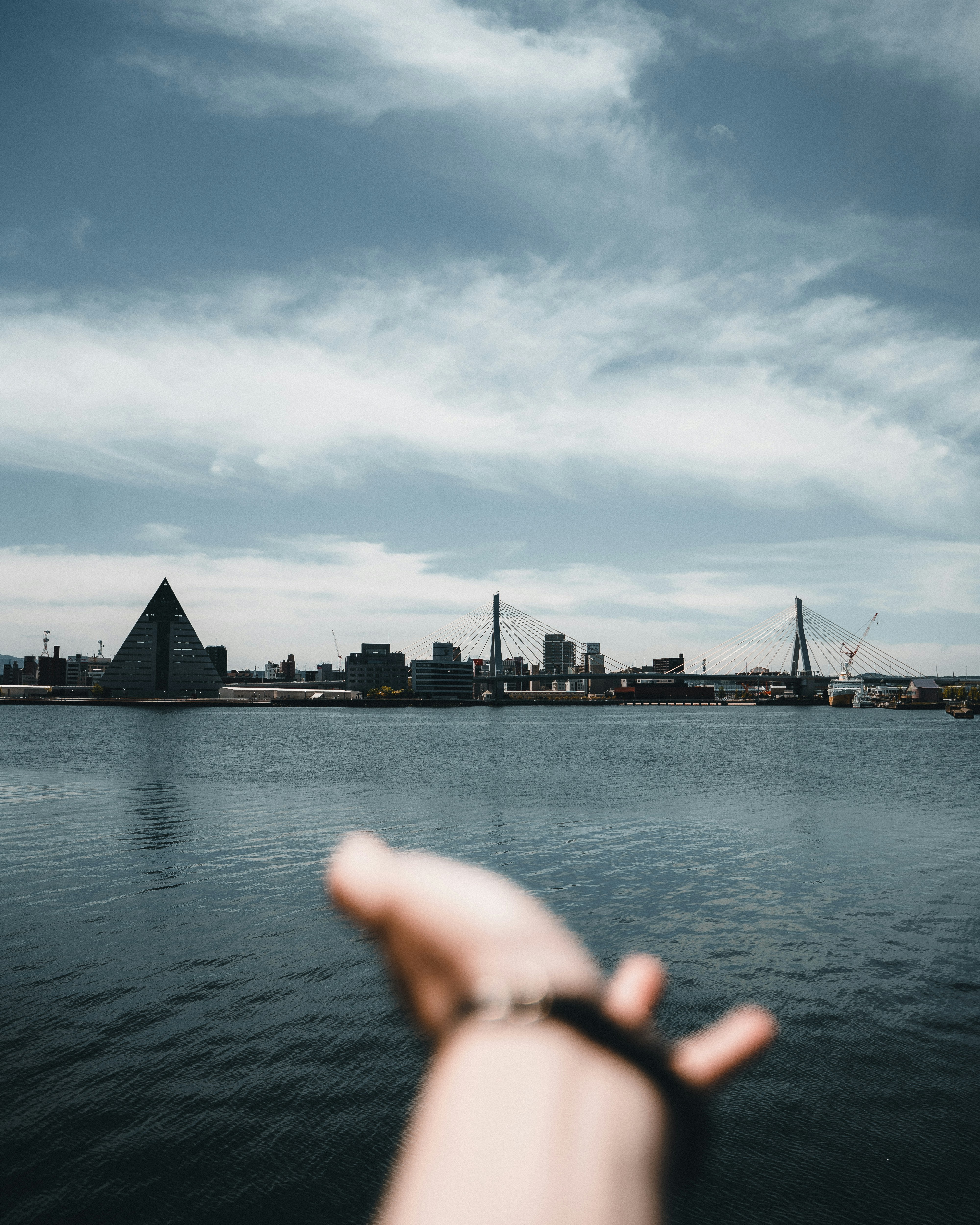 body of water near bridge under cloudy sky during daytime