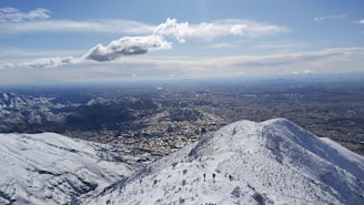 A panoramic view of a mountain range with a small group trekking along a ridge.