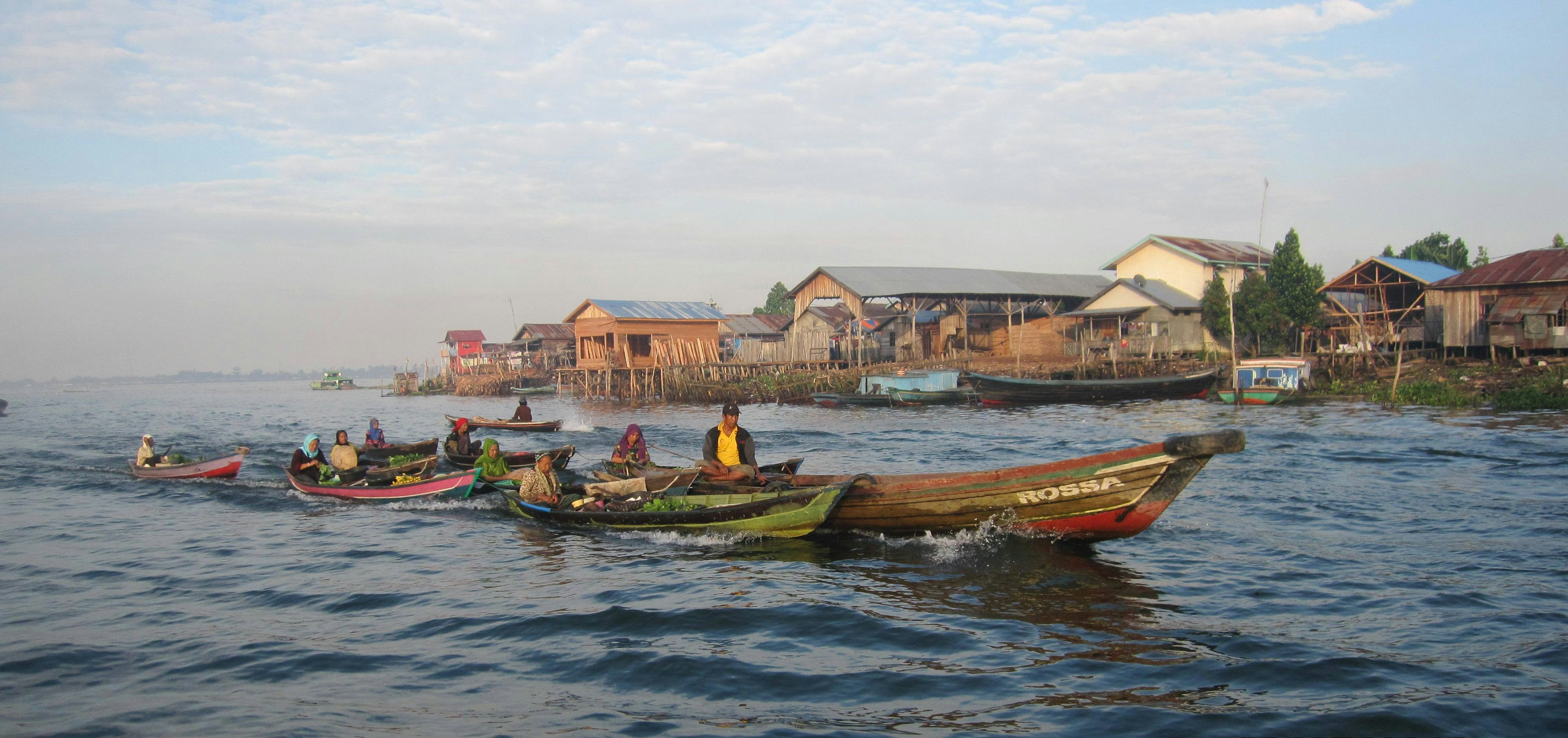 people riding on boat on water near houses during daytime