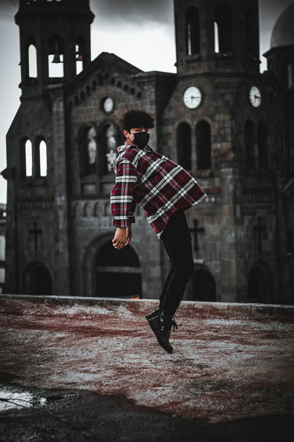 a man in a plaid shirt is dancing in front of an old building