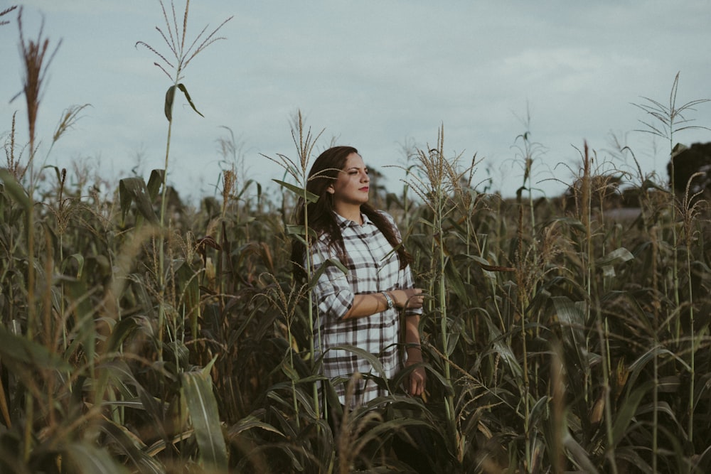 woman in red and black plaid shirt standing on corn field during daytime