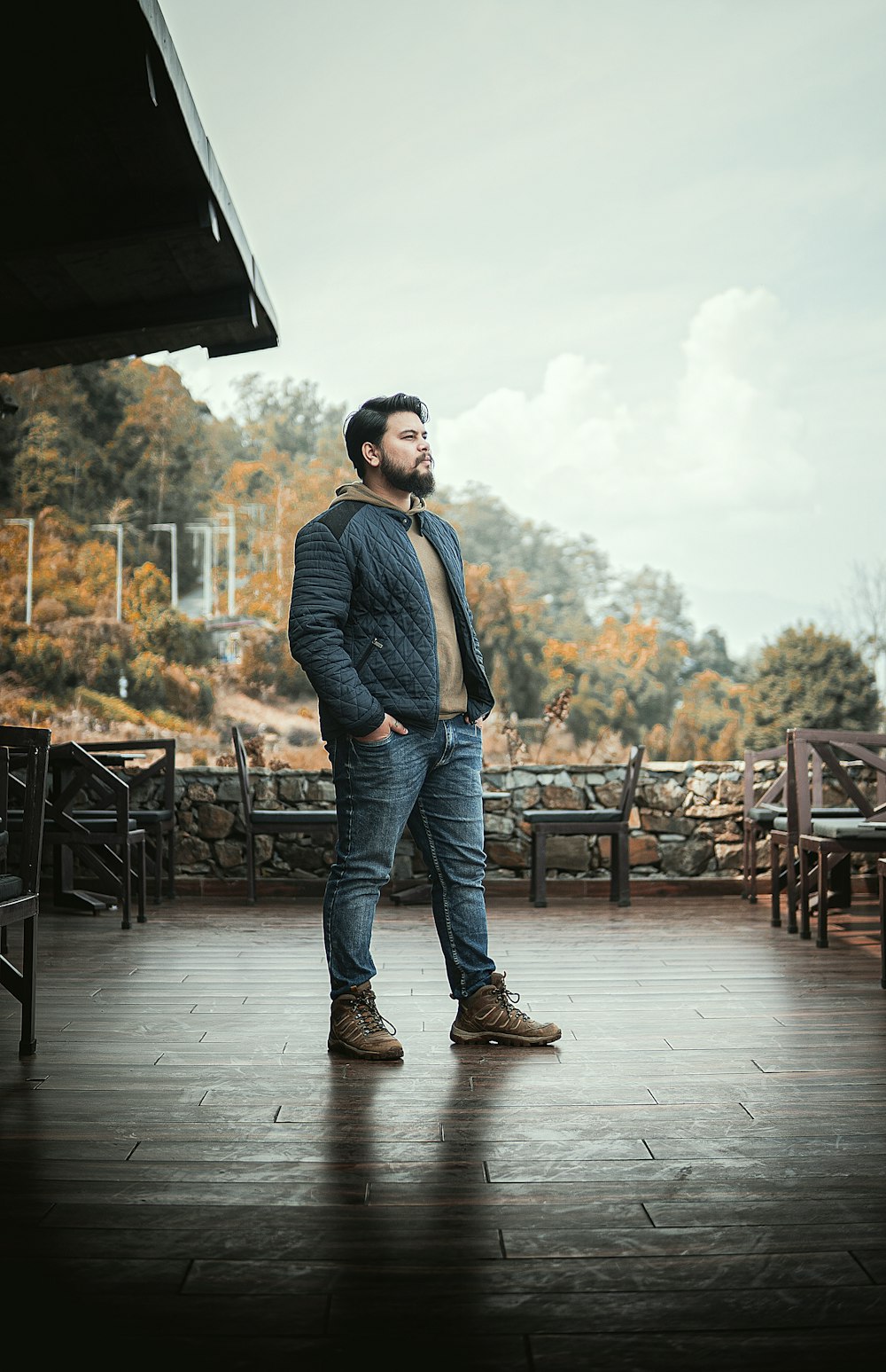 man in blue denim jacket and blue denim jeans standing on brown wooden floor during daytime