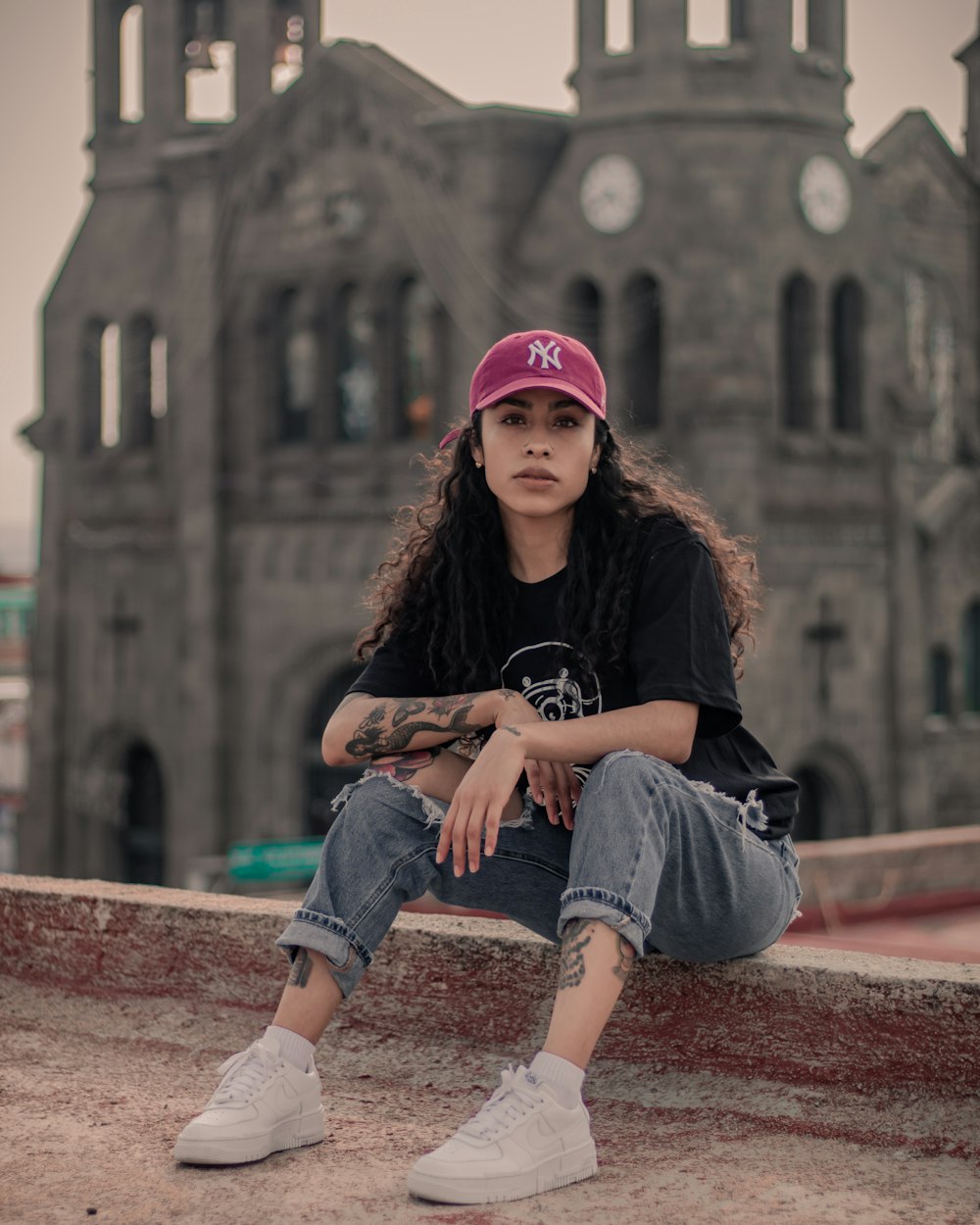 woman in black long sleeve shirt and blue denim shorts sitting on brown concrete bench during