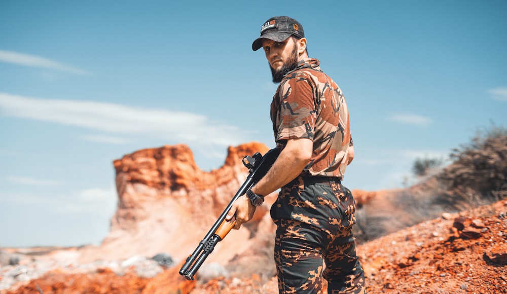 man in brown and black camouflage shirt holding rifle