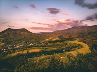 green trees and mountains under cloudy sky during daytime