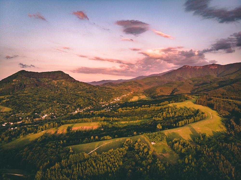 green trees and mountains under cloudy sky during daytime