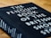 A close-up view of a hardcover book titled 'The Penguin Book of the British Short Story'. The book cover is black with white and teal text. It is placed on a wooden surface, slightly tilted to the right.