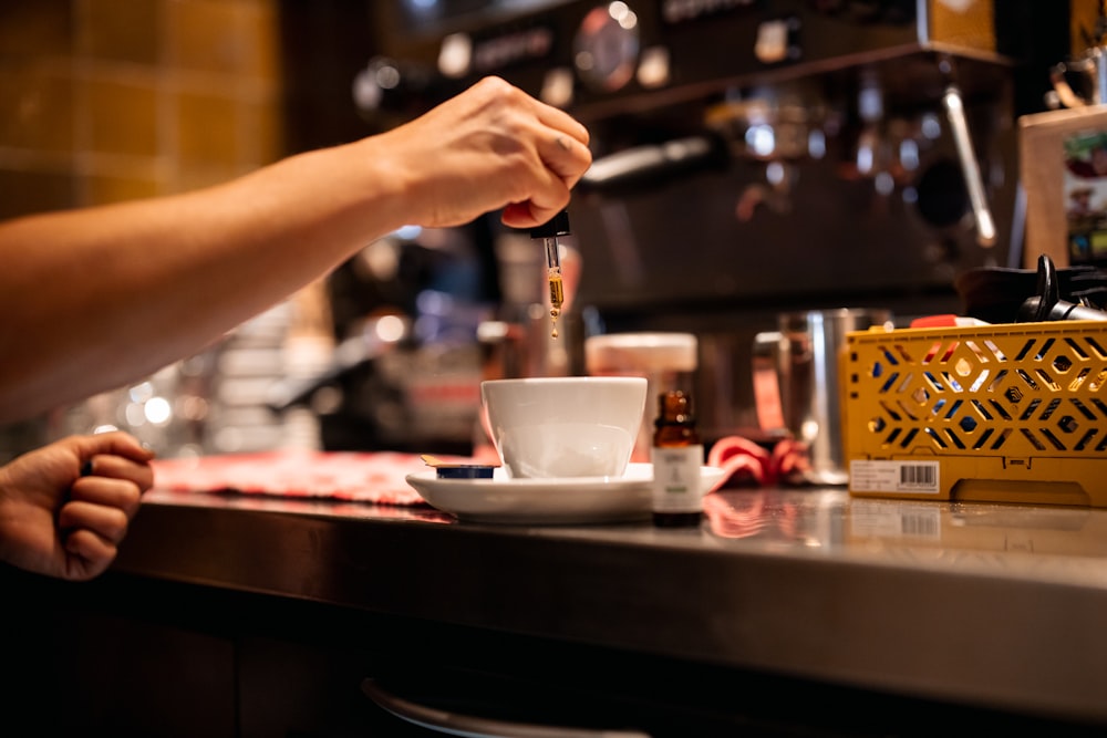 person pouring coffee on white ceramic teacup