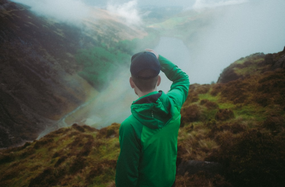 man in green hoodie standing on green grass field during daytime