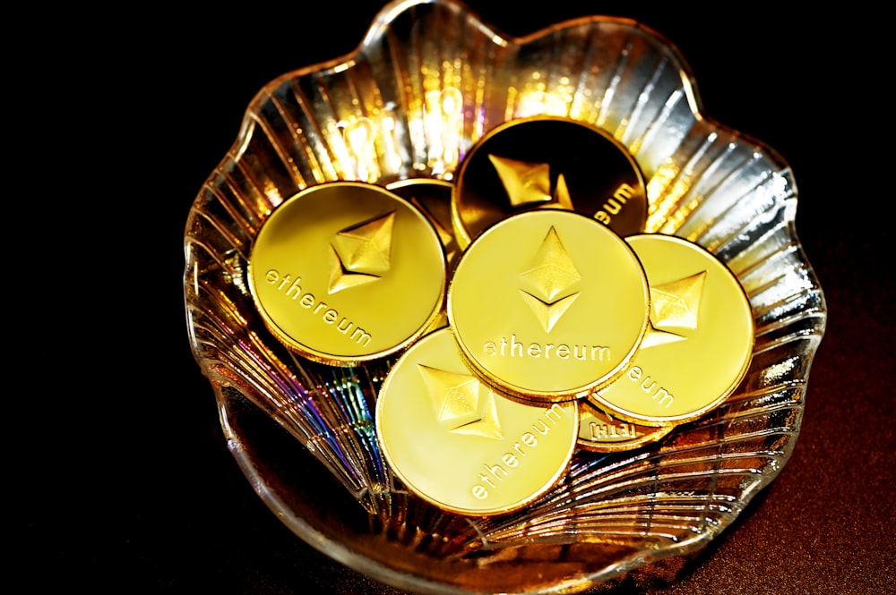 gold and silver round coins on clear glass bowl