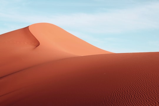 brown sand under blue sky during daytime in Erg Chebbi Morocco