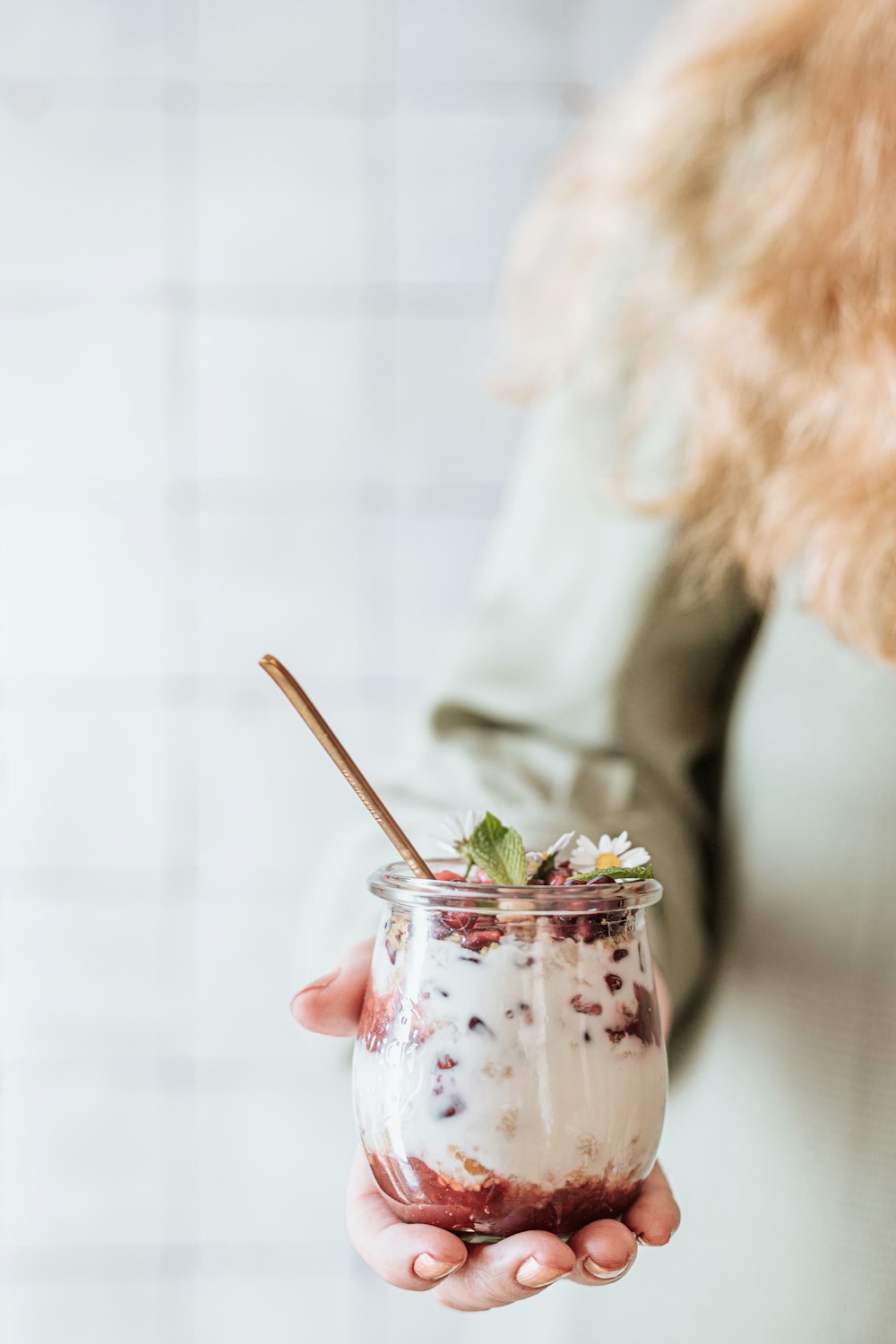 woman in white dress holding clear glass mug with green leaf