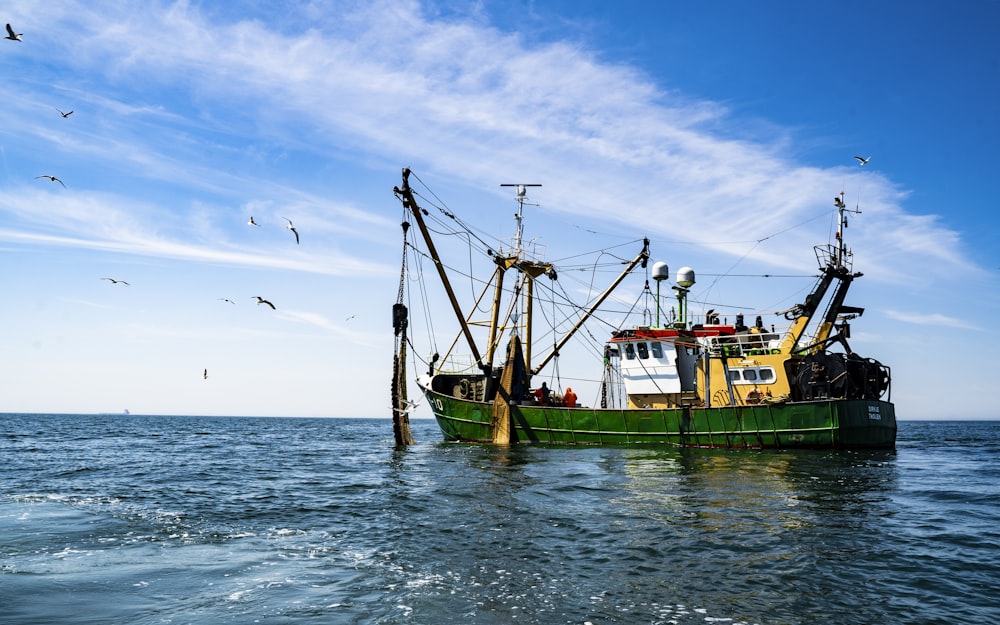 grünes und braunes Boot auf See unter blauem Himmel tagsüber