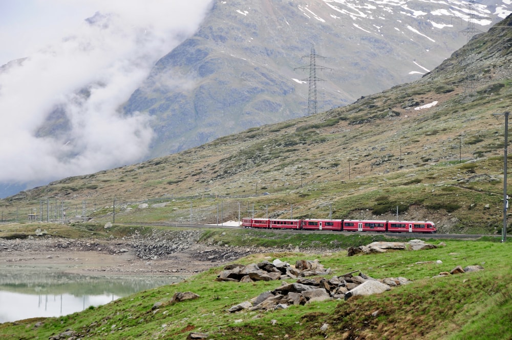 red and white train on rail near mountain during daytime