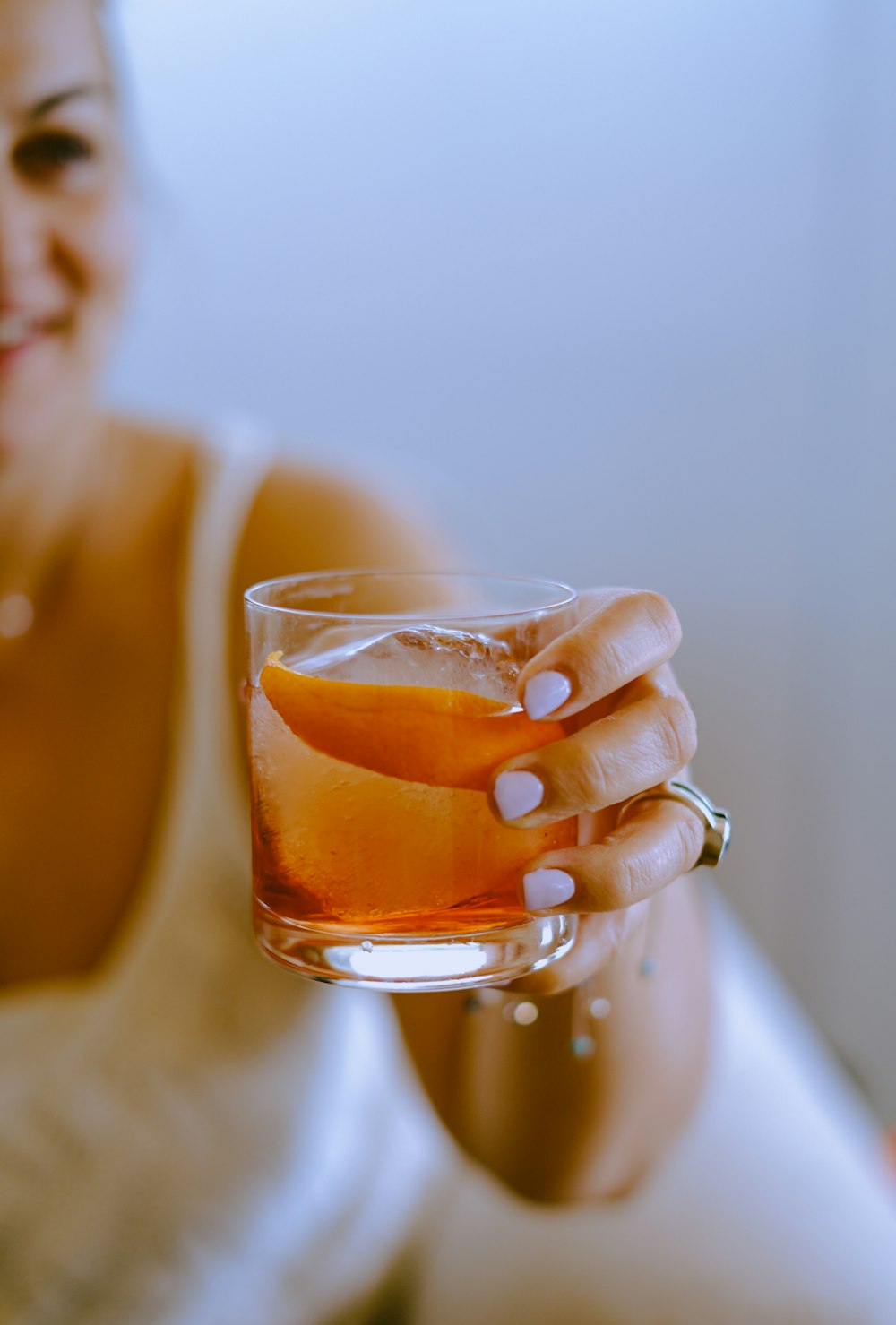 woman holding clear drinking glass with brown liquid