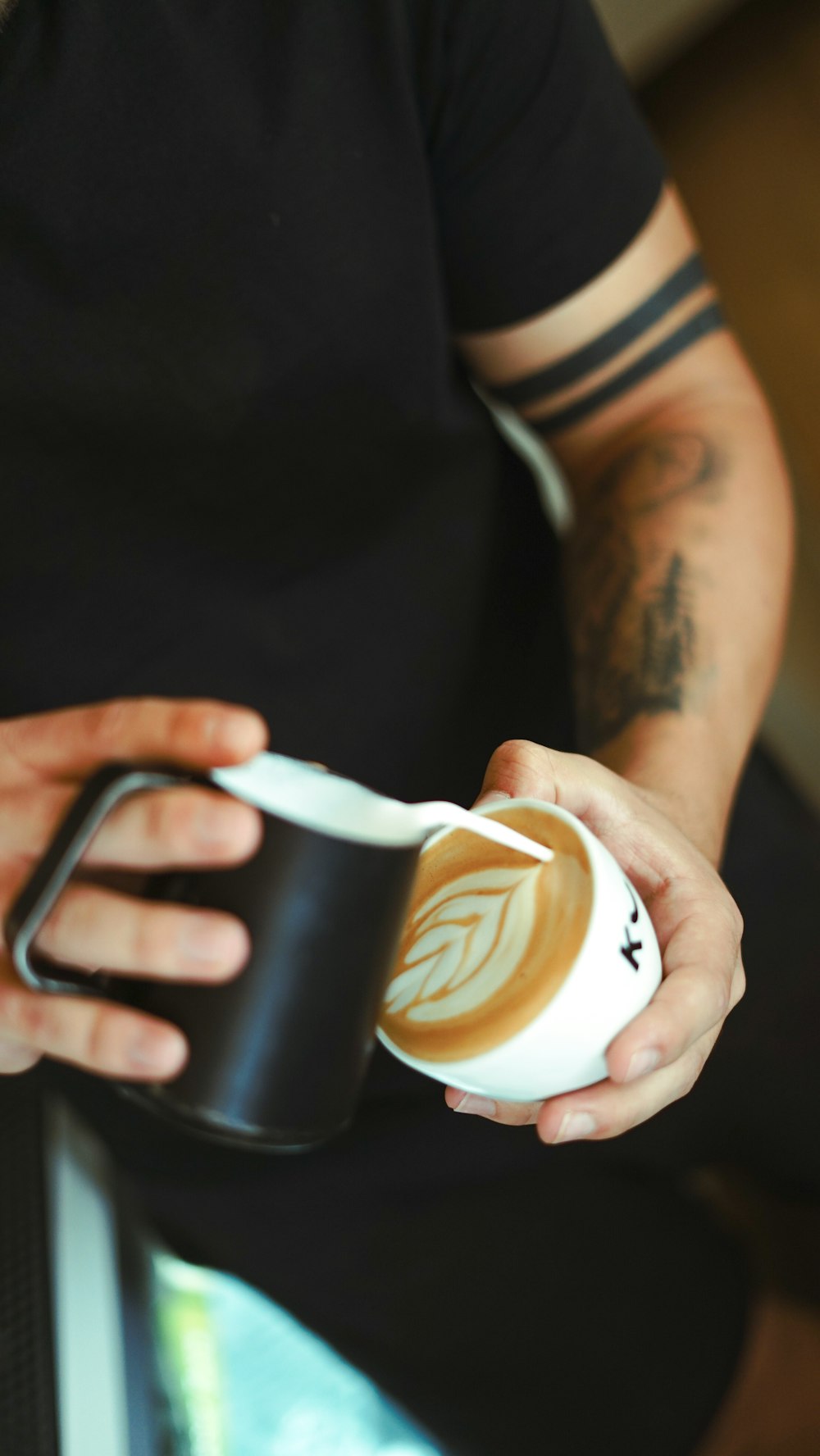 person holding black and white disposable cup with brown liquid