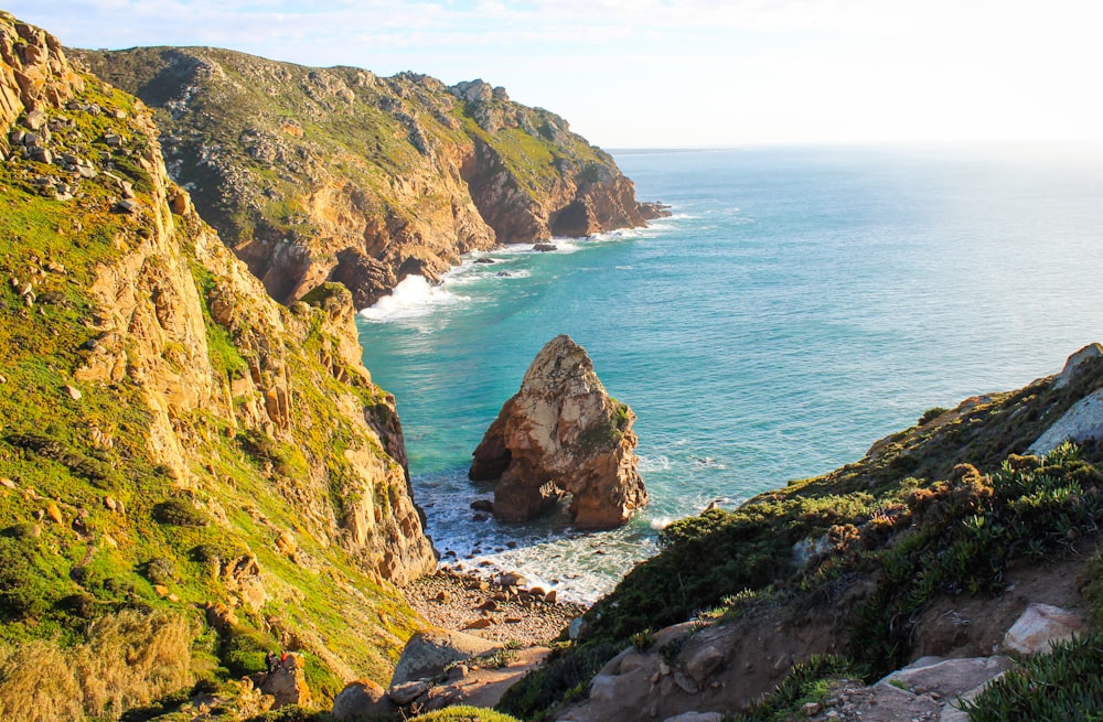 green and brown mountain beside sea during daytime