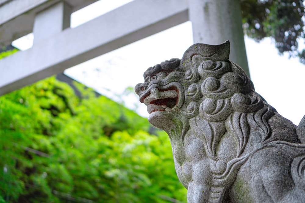 a stone statue of a lion in front of a gate